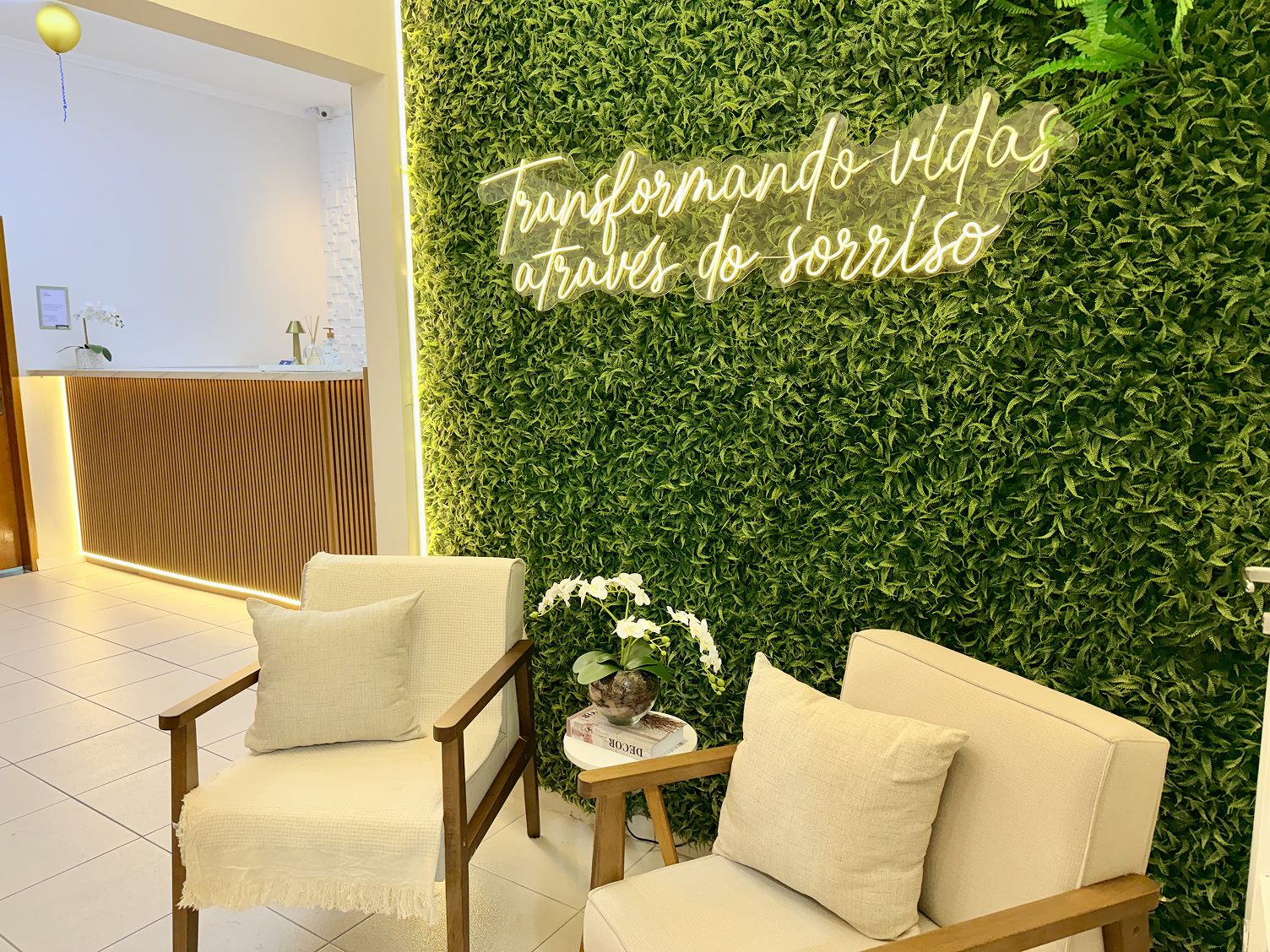 Recepção da Buono Odontologia com parede viva e letreiro luminoso 'Transformando vidas através do sorriso'