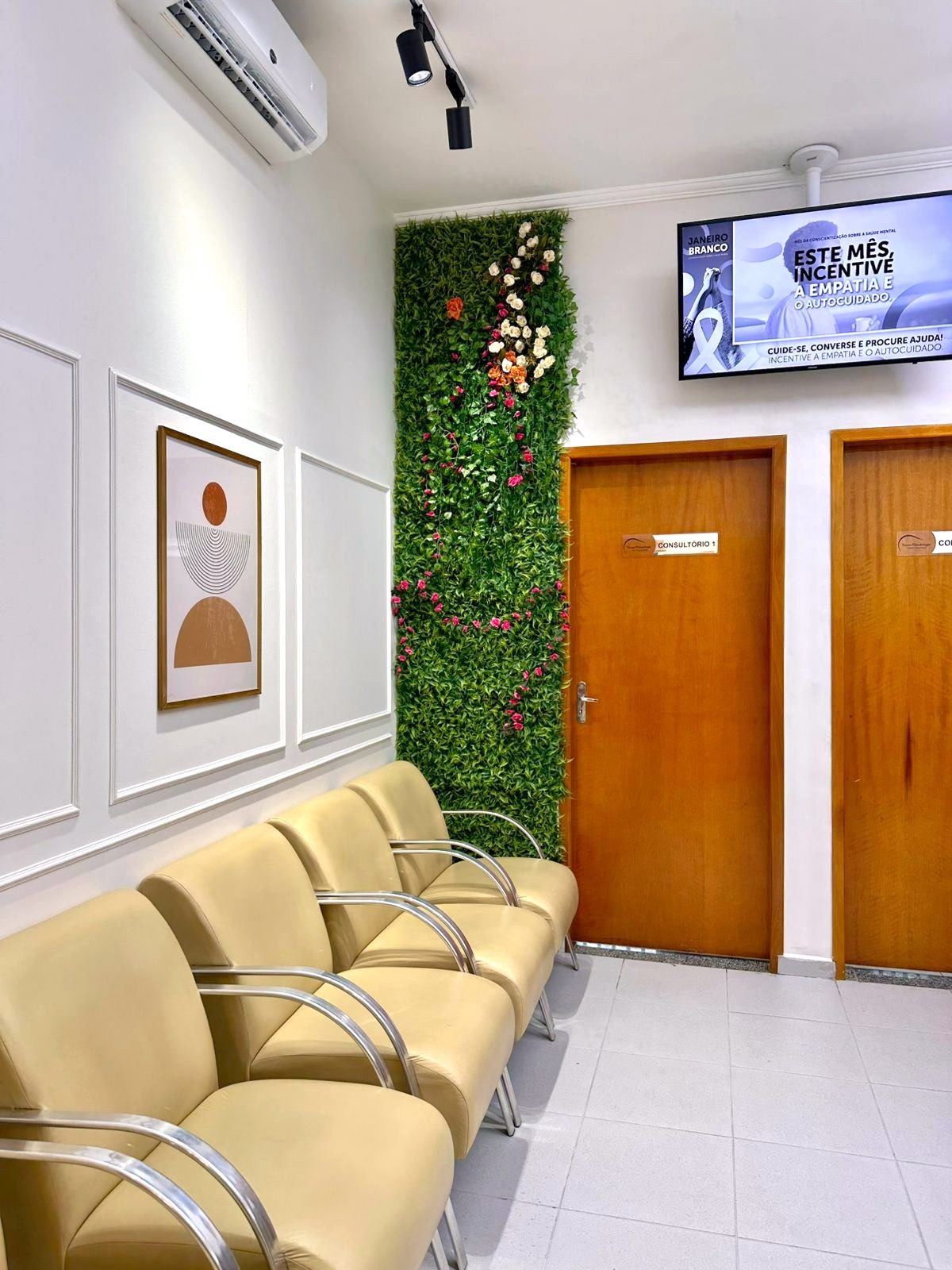 Sala de espera com poltronas, TV e quadros decorativos